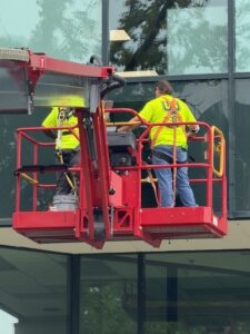 Universal Glass crew on an aerial lift replacing storefront glass panels in Mobile, AL